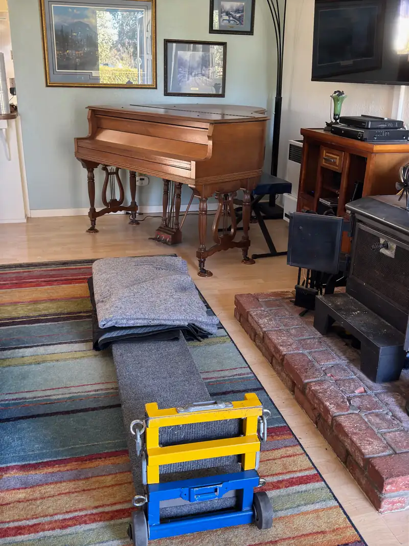Piano in a room with a moving ramp and piano dolly ready for transport in Grover Beach